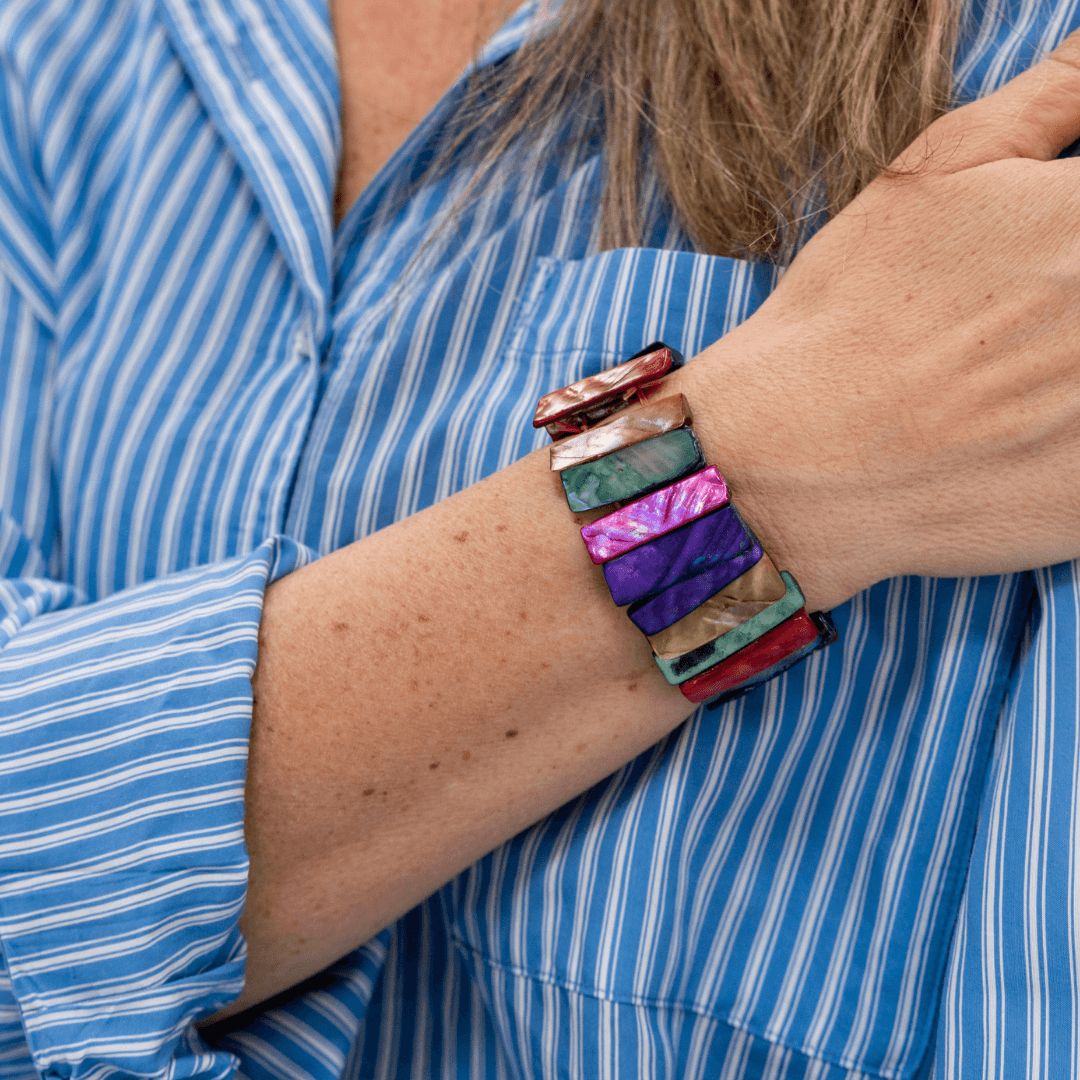 Parelmoer armband Rainbow Shell Slim gedragen om de pols met kleurrijke parelmoer delen in roze, paars, blauw en turquoise tinten