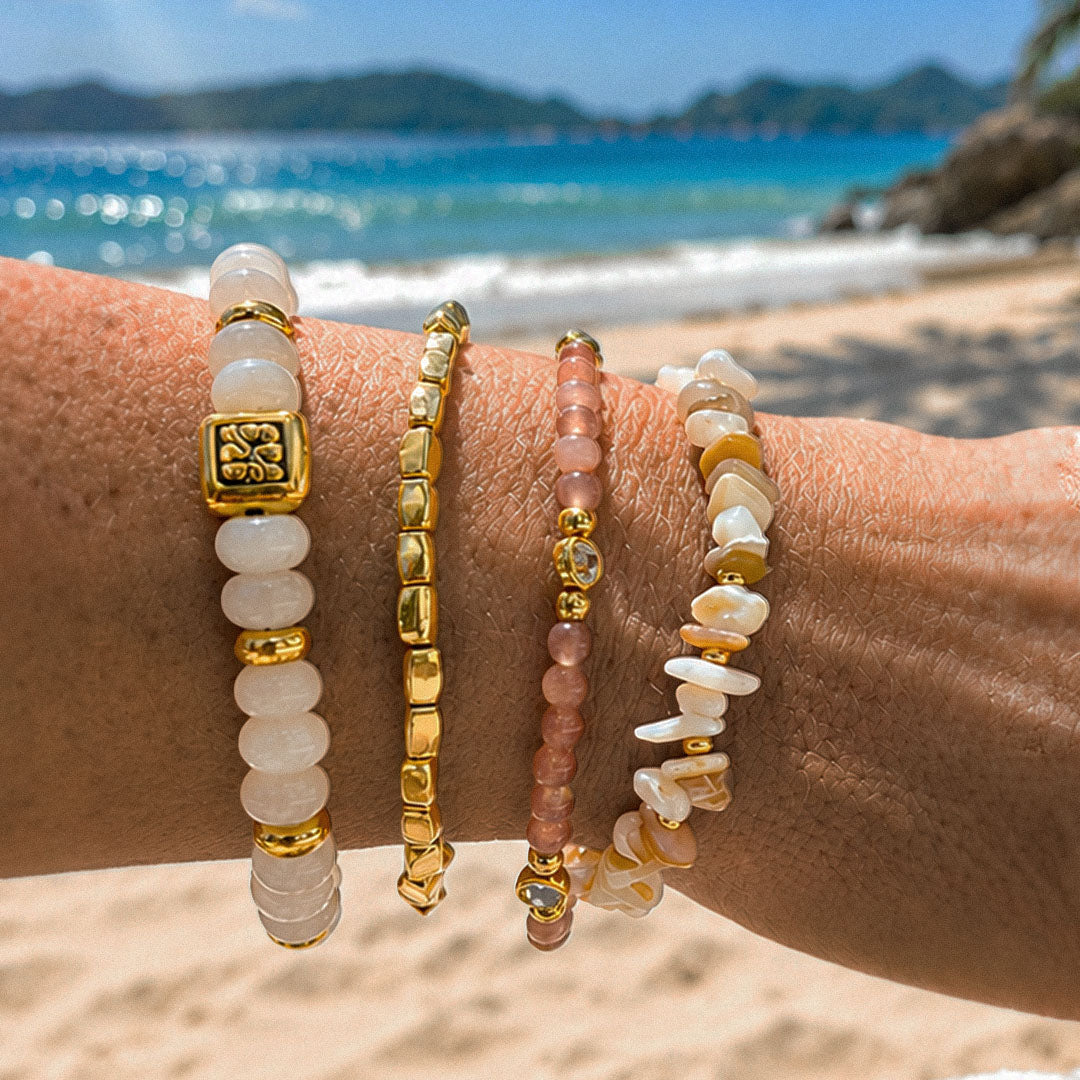Armbandenset Pearl Blush met roze, witte en goudkleurige kralen gedragen op het strand