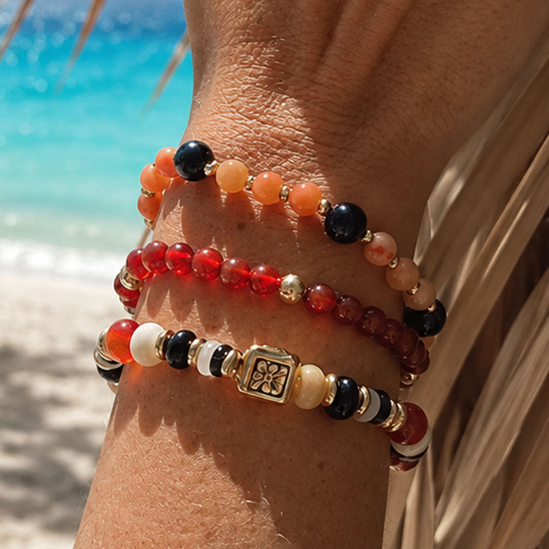 Armbandenset Sunset Mix met rode, oranje en zwarte kralen gedragen op het strand