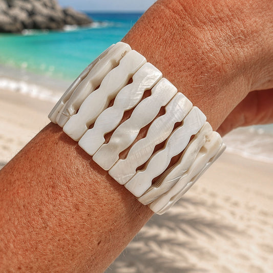 Brede parelmoer armband Wave met witte golvende schakels gedragen op het strand