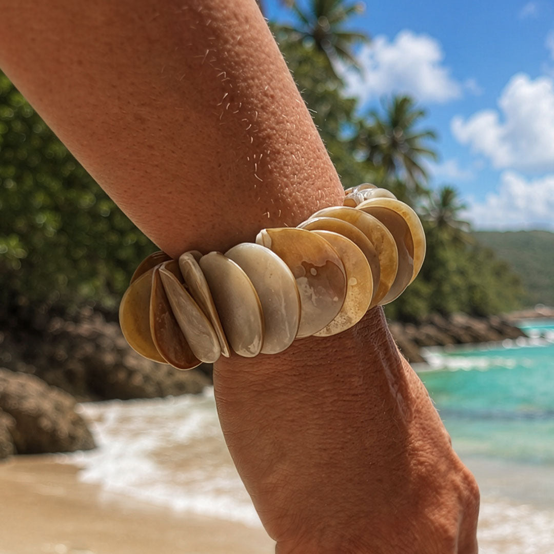 Parelmoer armband Luna Sand met ronde beige en zandkleurige schakels gedragen op het strand