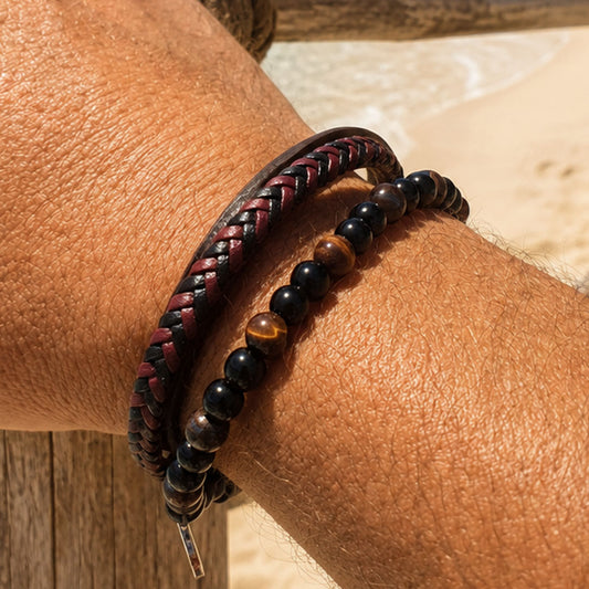 Zwart-rode vegan leren herenarmband met kralen om een mannenpols op het strand.