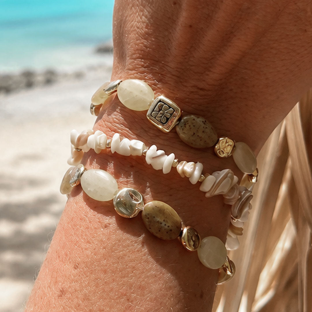 Armbandenset Sand met witte schelpdetails en natuurstenen kralen gedragen op het strand