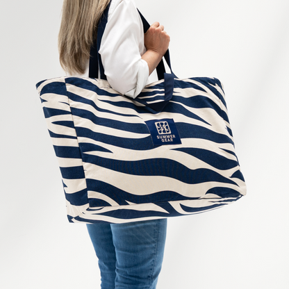 Grote strandtas Onda XL met 2 handvaten die volledig afsuit met rits van  canvas in de kleur blauw en naturel zijzicht op model