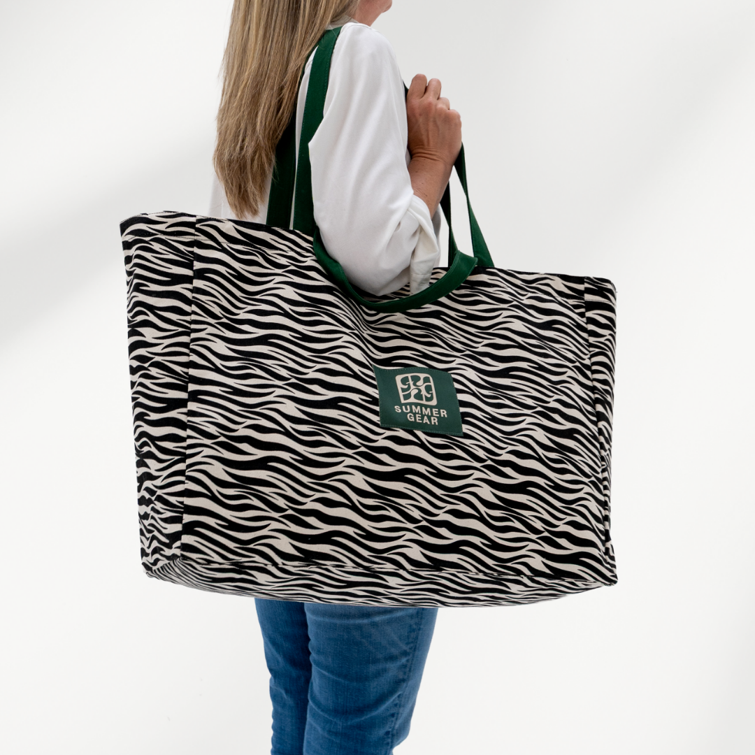 Grote strandtas Savan XL met 2 handvaten die volledig afsuit met rits van  canvas in de zeebraprint zijkant op model