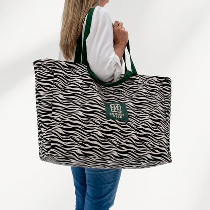 Grote strandtas Savan XL met 2 handvaten die volledig afsuit met rits van  canvas in de zeebraprint zijkant op model