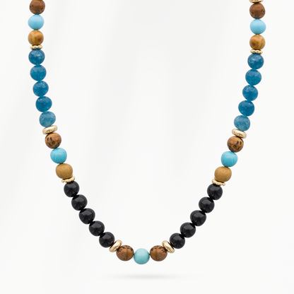 Detail van de Ocean Blue kralenketting voor heren met helderblauwe, turquoise en zwarte kralen, bruine accenten en goudkleurige tussenkralen.