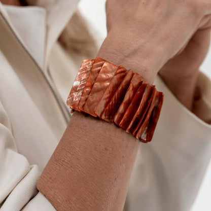 Brede roodbruine parelmoer armband Amber Shell gedragen om de pols