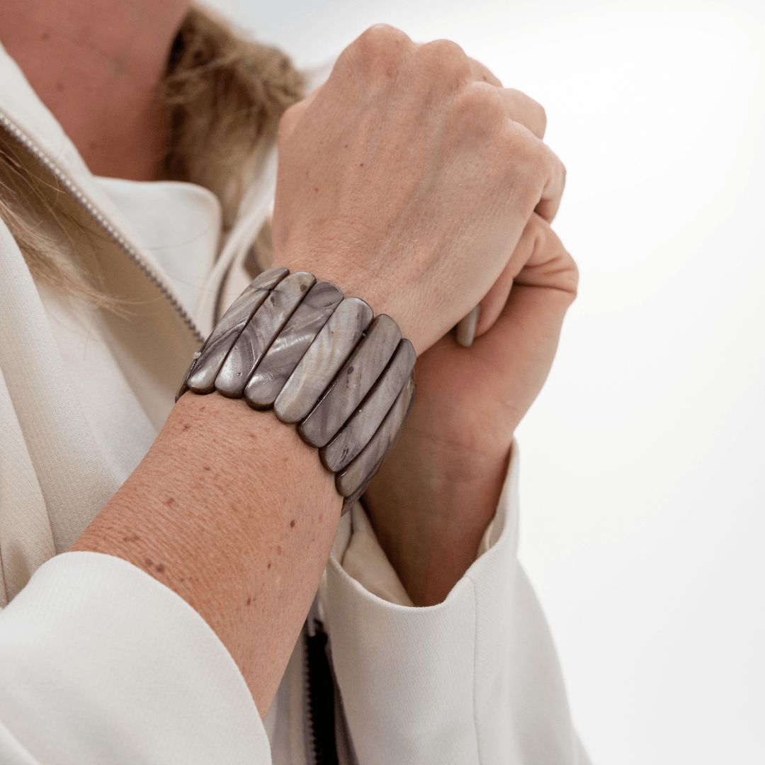 Brede Stone parelmoer armband met natuurlijke grijze glans om de pols