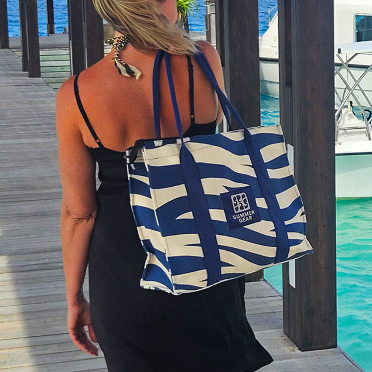 Canvas tote bag gedragen op de pier bij zee tijdens zomers moment.